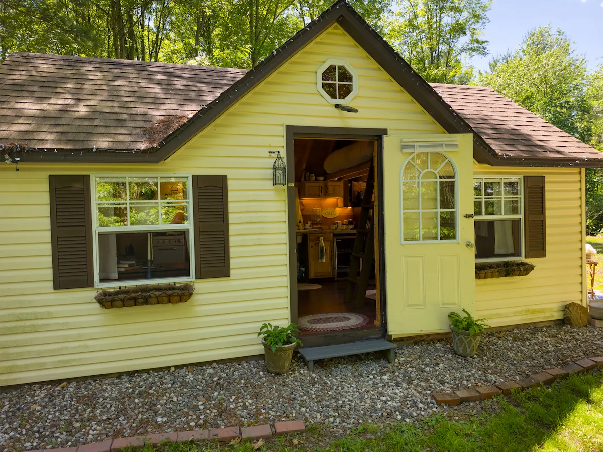 The yellow Bridal Suite cottage seen from the front, door open to the warm interior