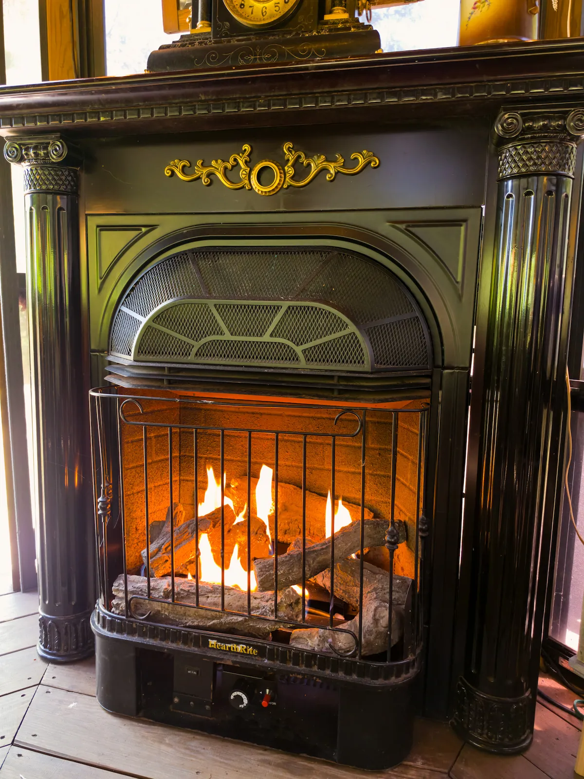 A black Victorian gas fireplace glowing warm inside the gazebo, an antique clock above
