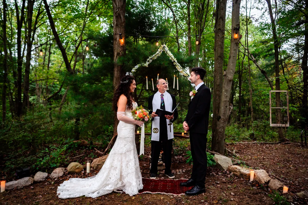 The ceremony in the woodland chapel, candles lit behind the couple