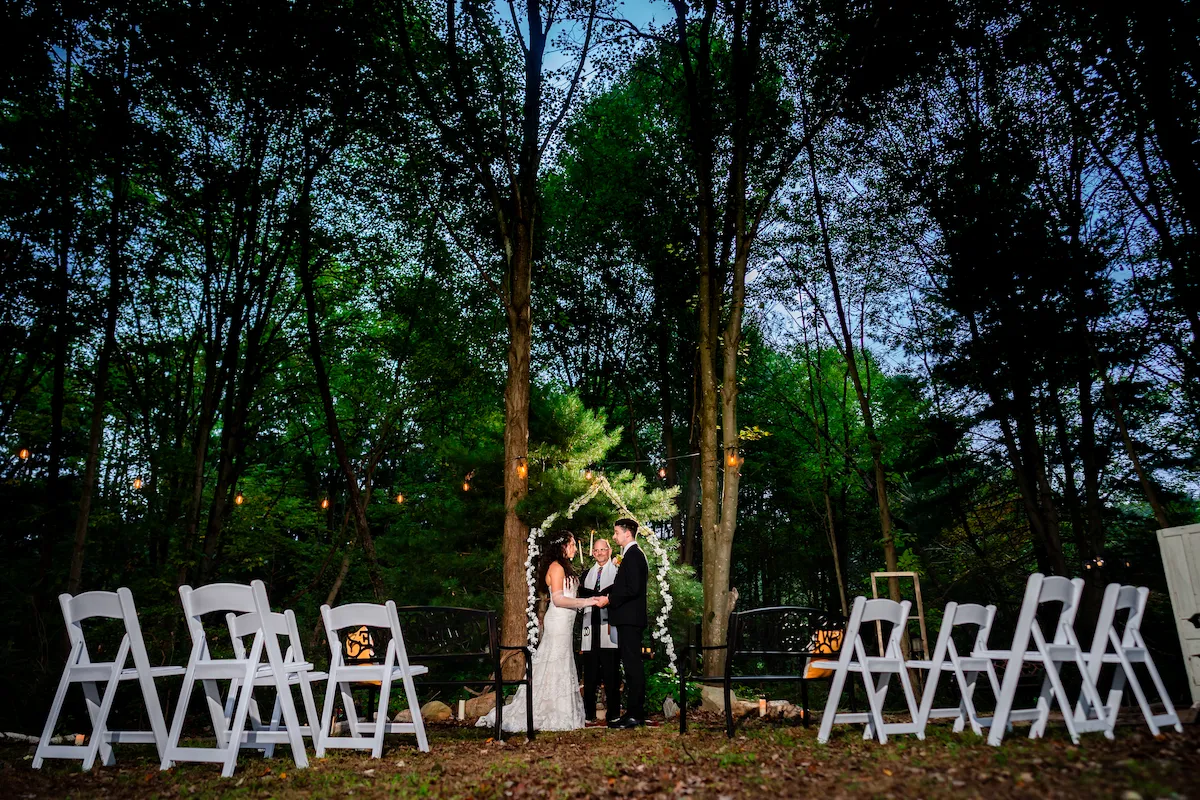 The woodland chapel at dusk, string lights glowing above the ceremony