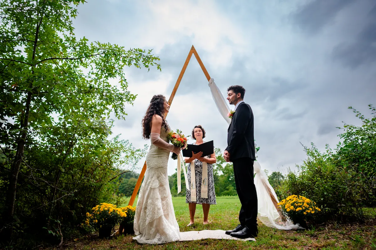 Alex and Naomi exchange vows beneath the A-frame arch with the officiant