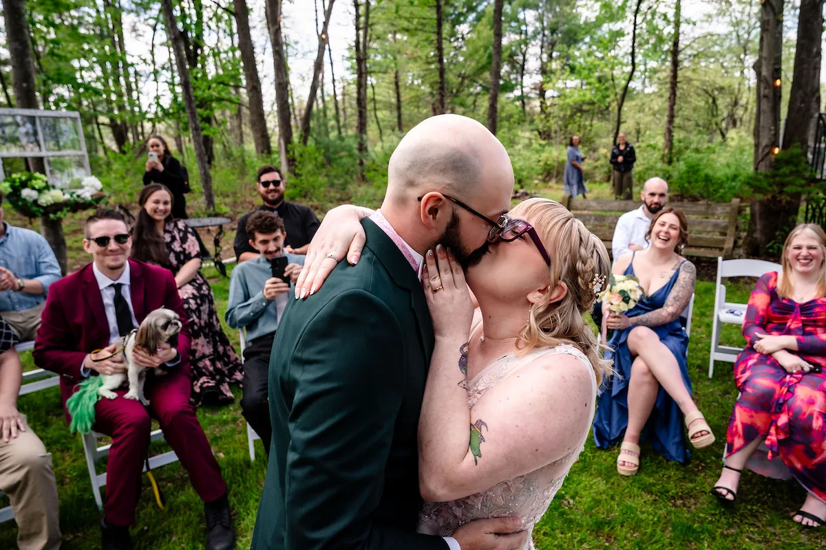 Tera and Matt during the ceremony, guests seated in the woods around them