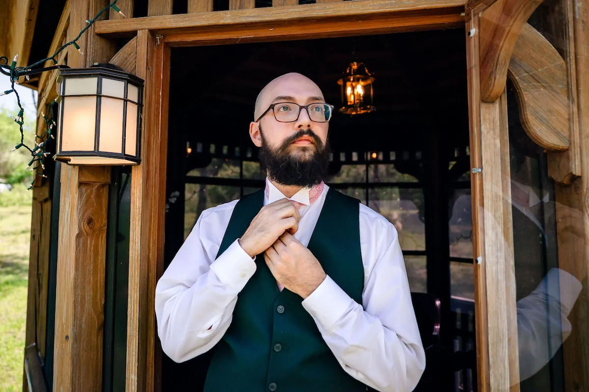Matt adjusts his tie in the doorway of the Groom's Gazebo